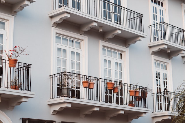 Exterior of a light blue apartment building with white doors and black iron balconies